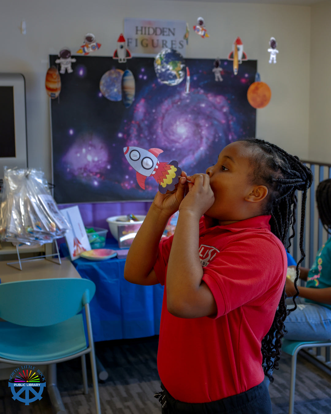 A child in a red polo shirt launches a straw-powered rocket during Community Night at Argenta Library.