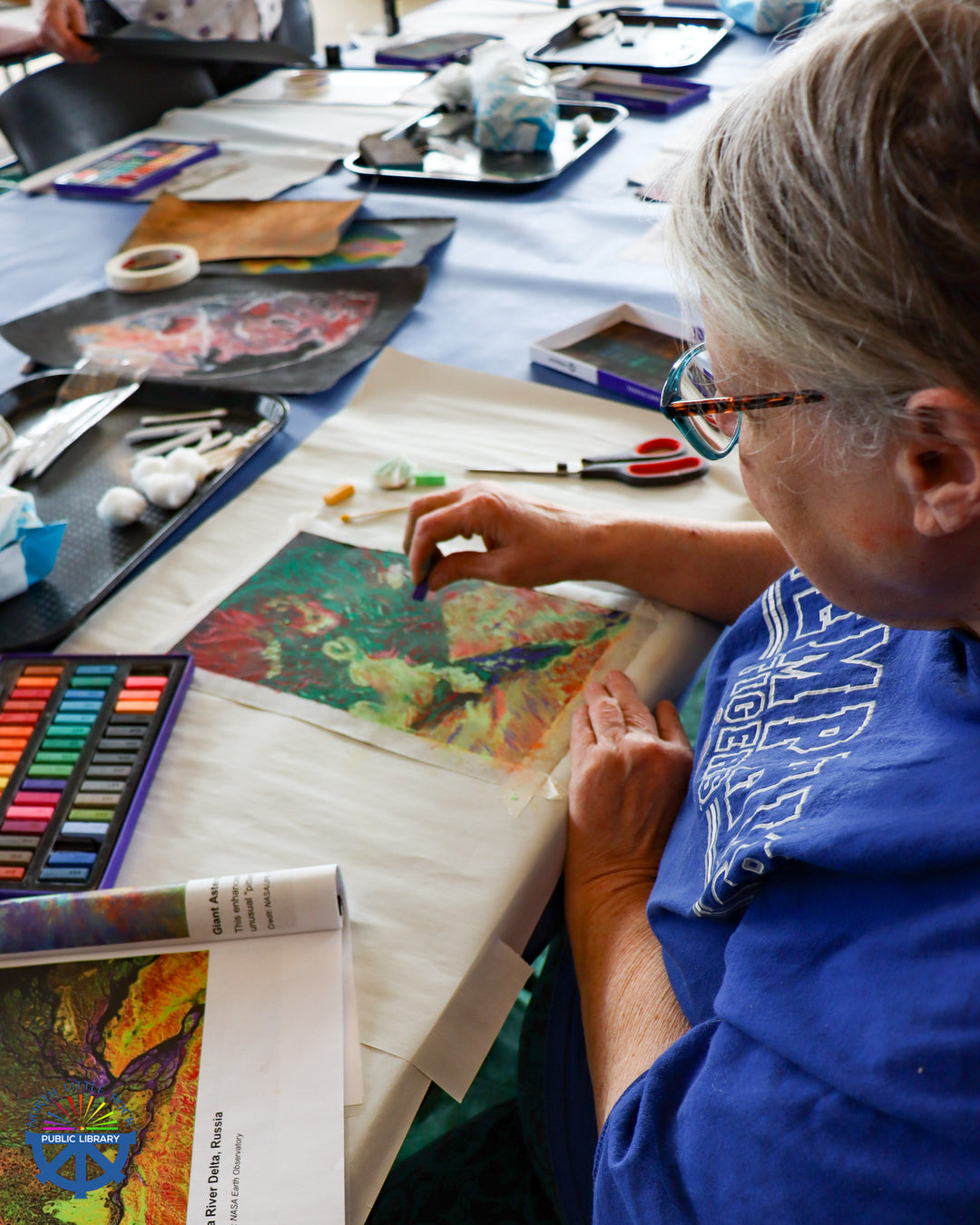A library patron creates a work of art inspired by space photography with colorful pastels.