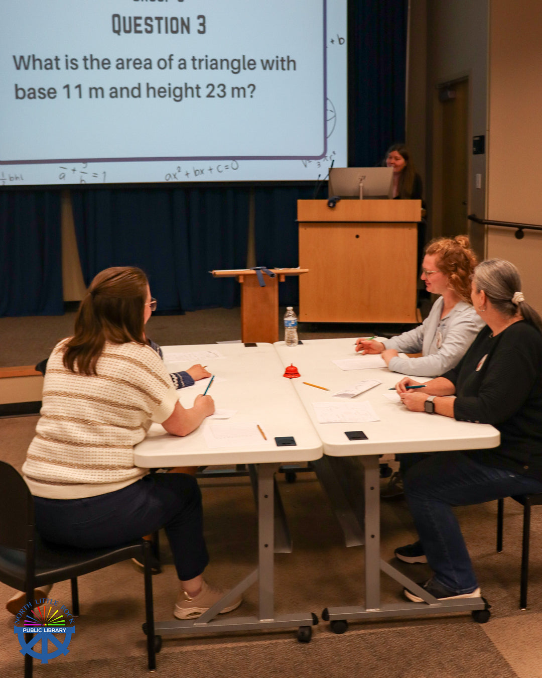 Four people sit at a table completing math problems during a Hidden Figures-themed mathletes competition.