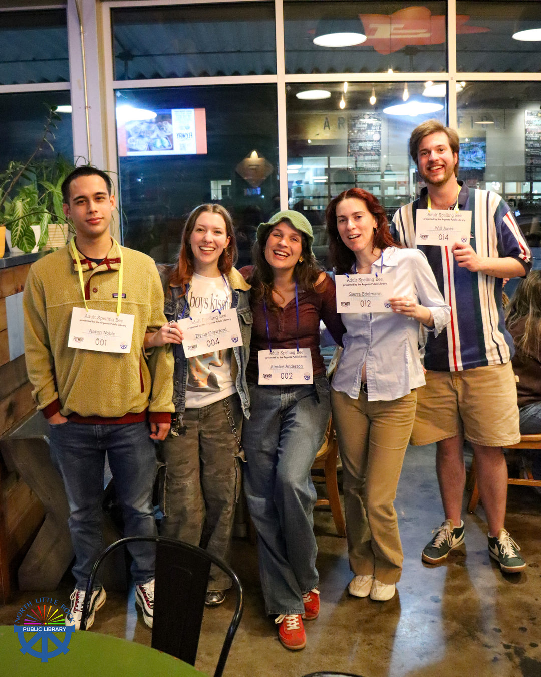 A group of adult spelling bee participants pose with their name tags at a local brewery. 