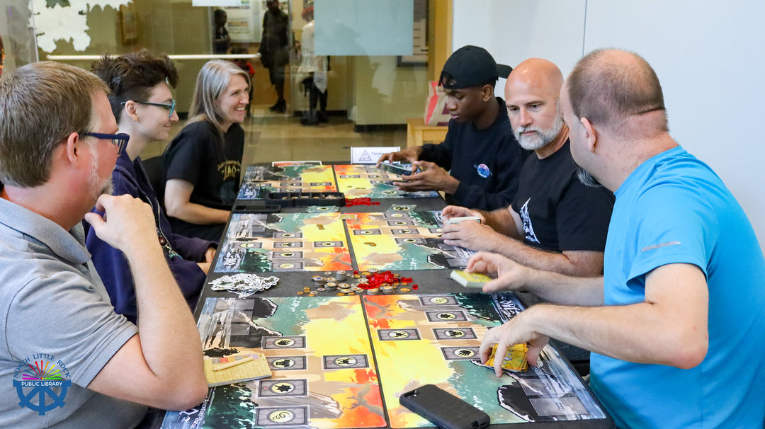 Group of people playing a board game together in a casual setting during laman con tournaments.