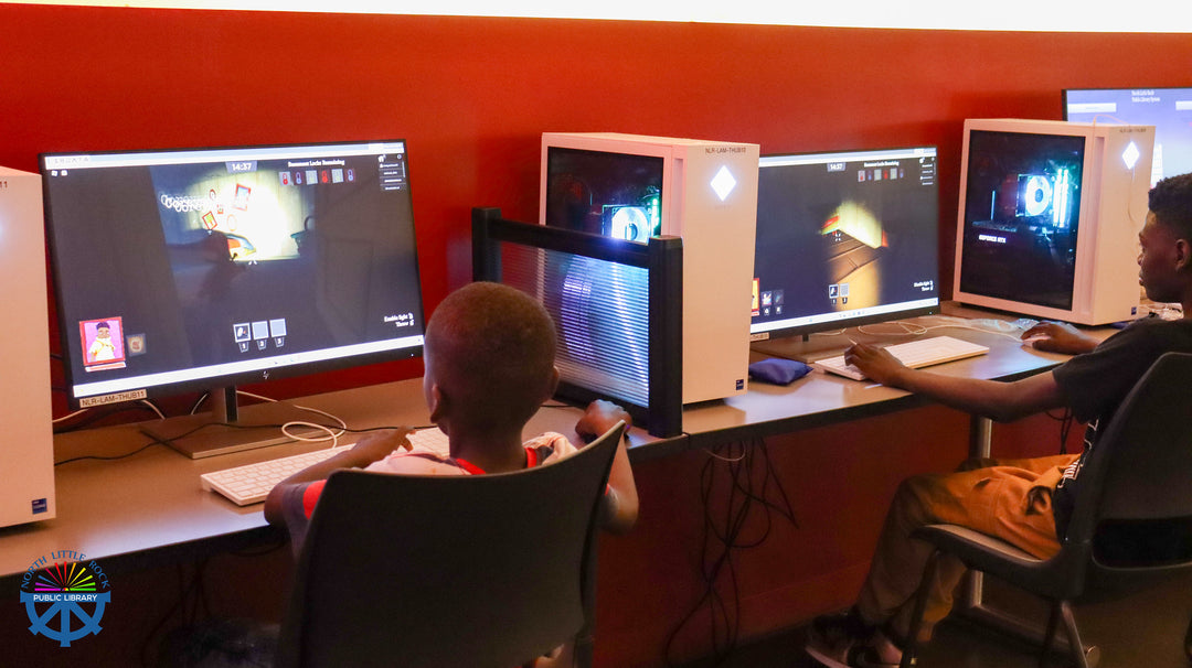 Two people sitting at a row of computer stations in the Library Computer Lab during the laman con gaming tournaments.