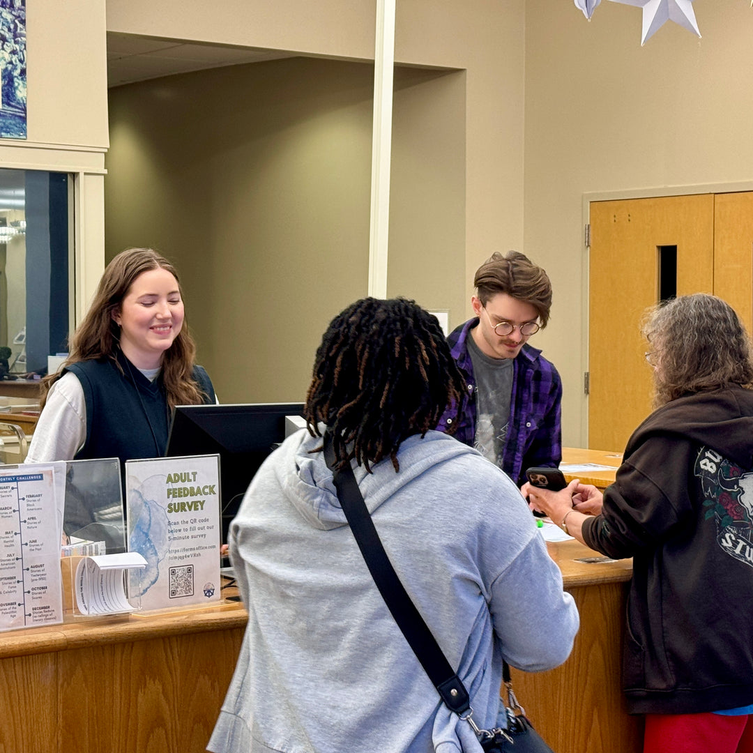 Librarians at the service desk helping patrons release their prints to the library wireless printer.