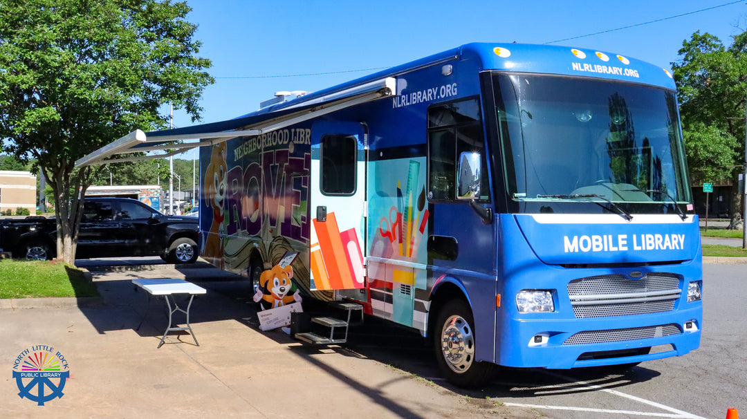 Blue mobile library bus parked on a sunny day with trees in the background