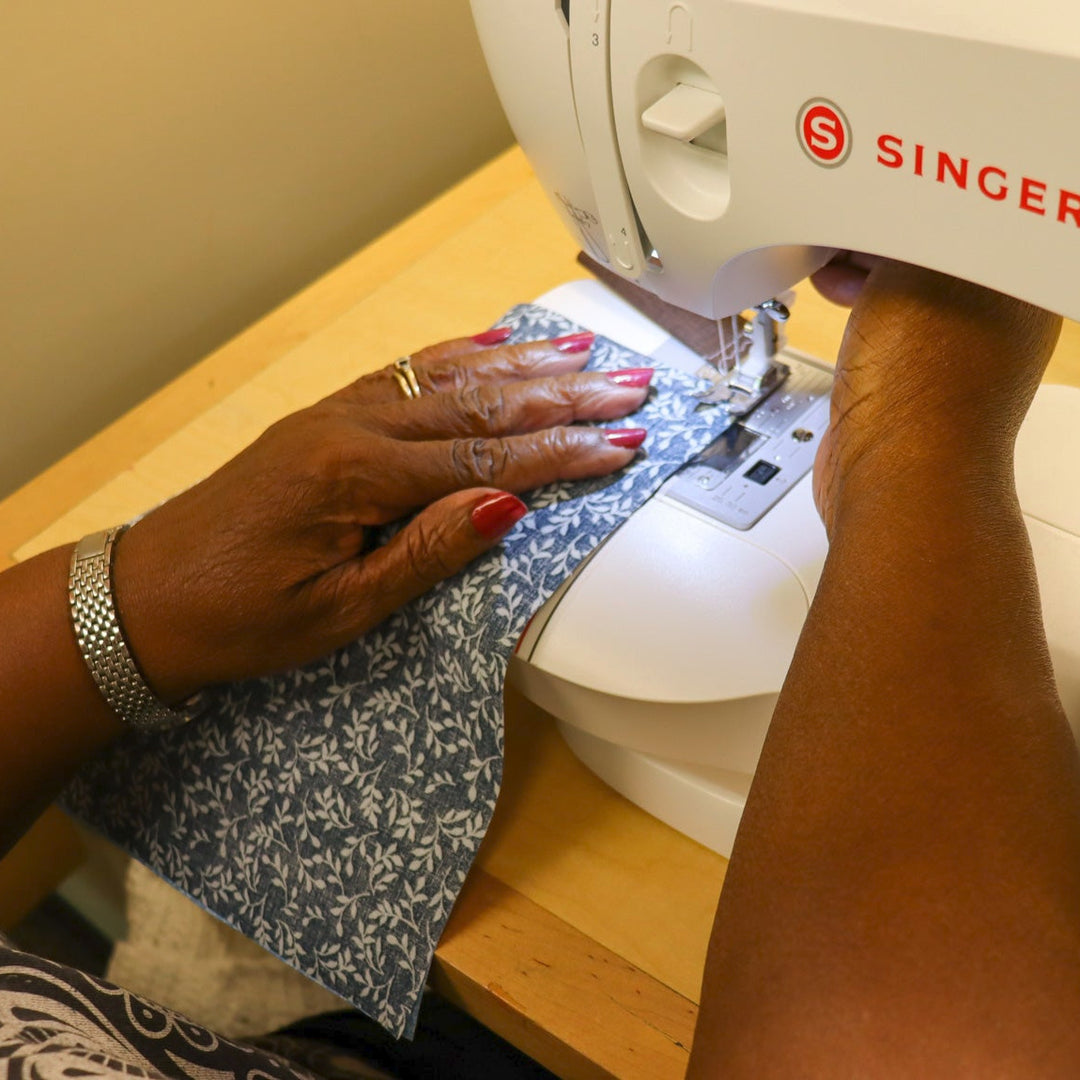Person sewing patterned fabric with a sewing machine.