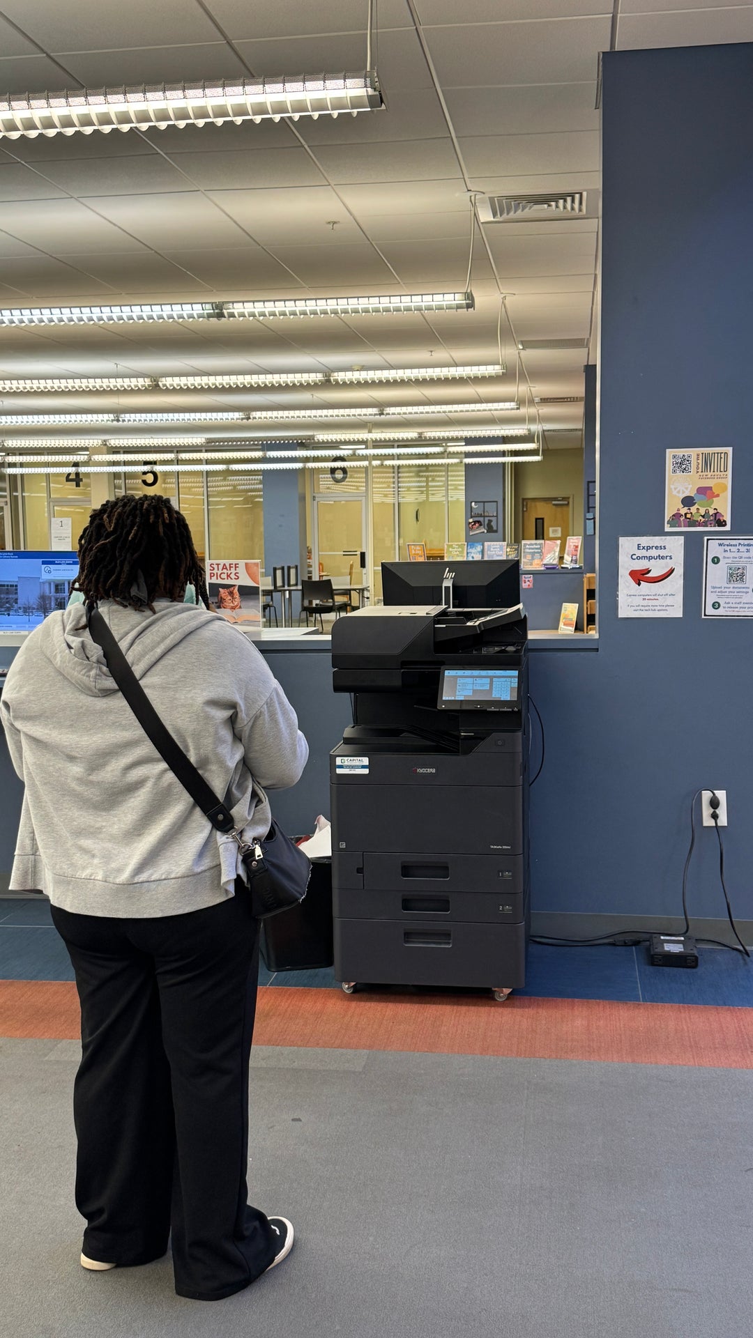 A library visitor waits in front of the wireless printer for their print to begin running.