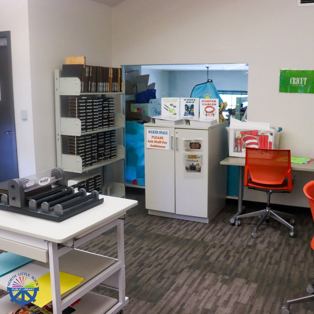 A die-cut machine with shelves of dies and a cabinet with signs about various tools inside.