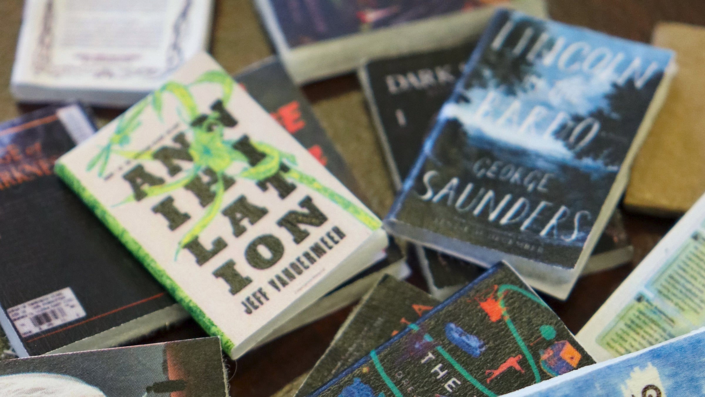 A pile of small books on a wooden table.