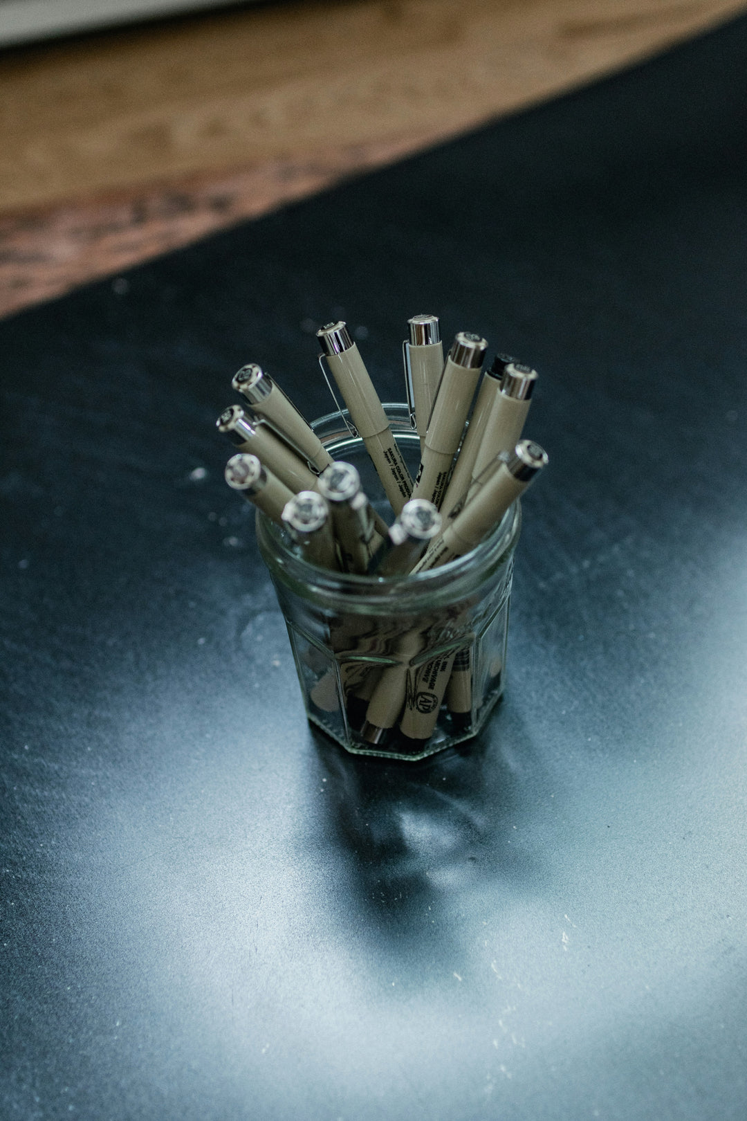 A jar of black ink pens for signing documents.