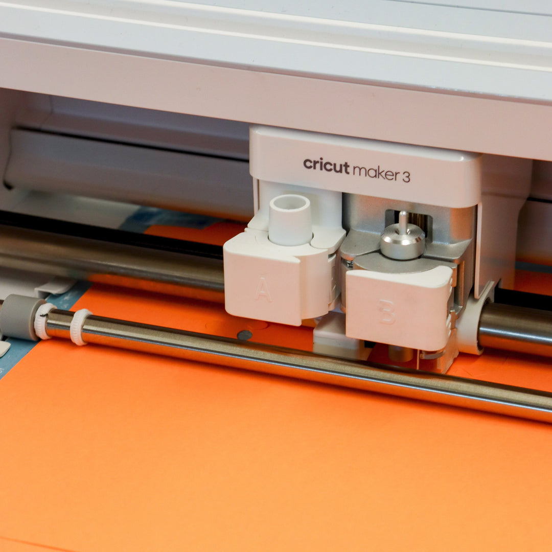 Cricut machine cutting orange paper.