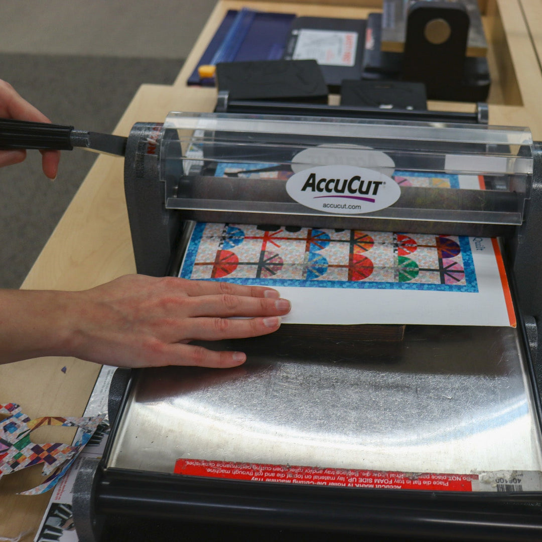 A person using a die-cut machine to cut shapes out of paper.
