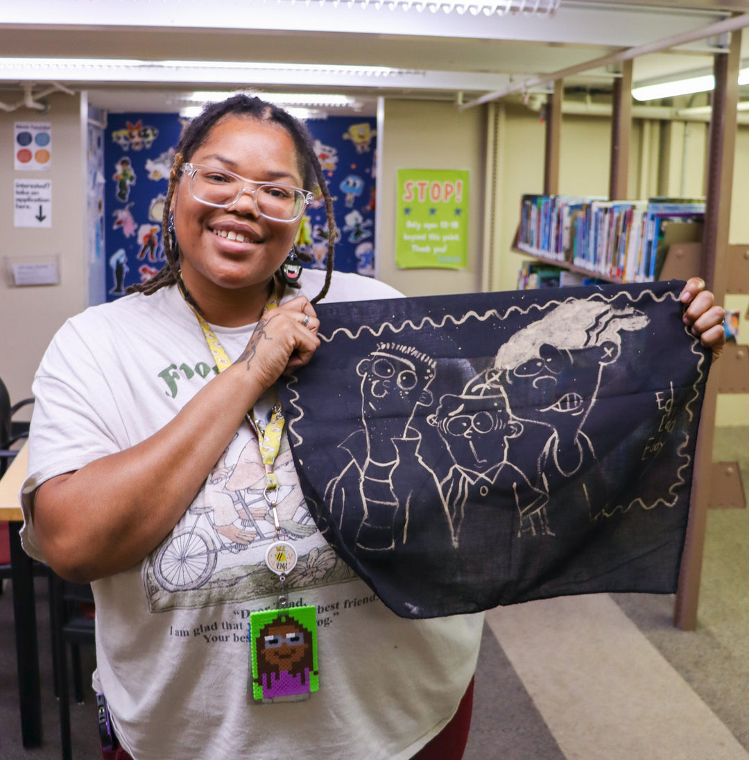 Tween programmer Drienne holding a bleach-painted piece of black cloth.