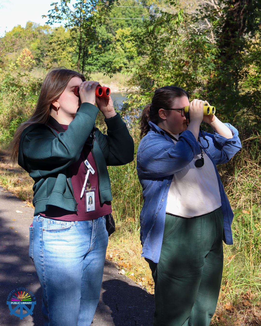 Two birdwatchers using colorful binoculars in a wooded area.