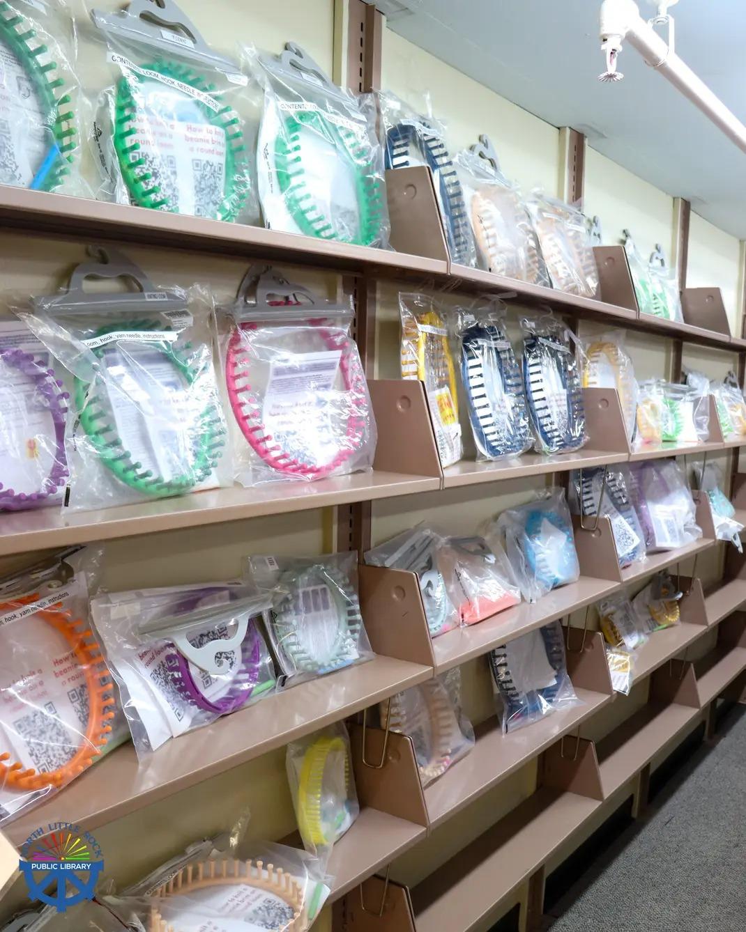 Tan metal shelves with colorful knitting looms in plastic bags.