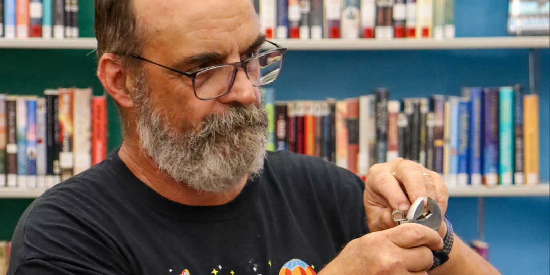 Closeup of a man with glasses holding a crescent wrench.