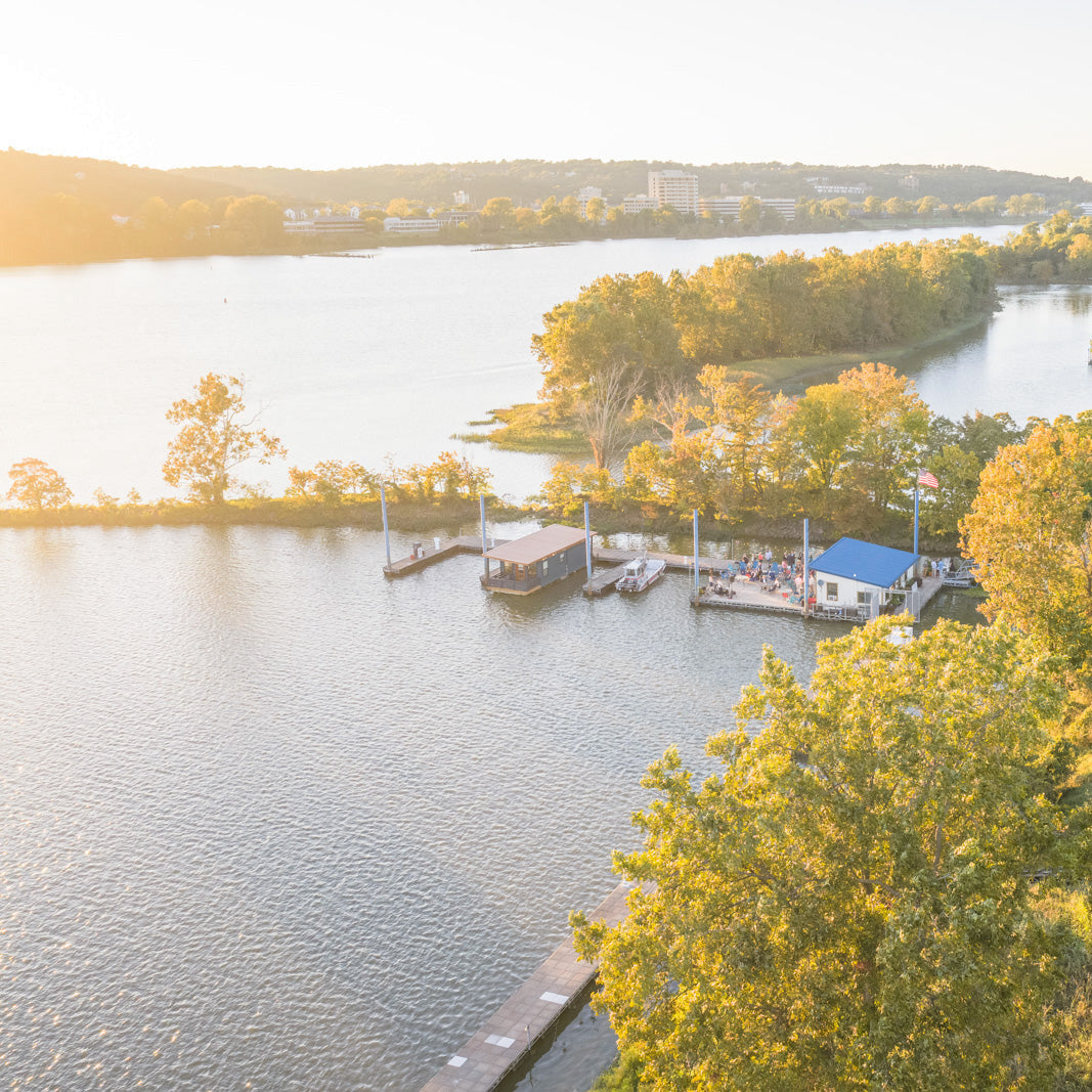 The Arkansas River with trees growing on islets and people on a dock.