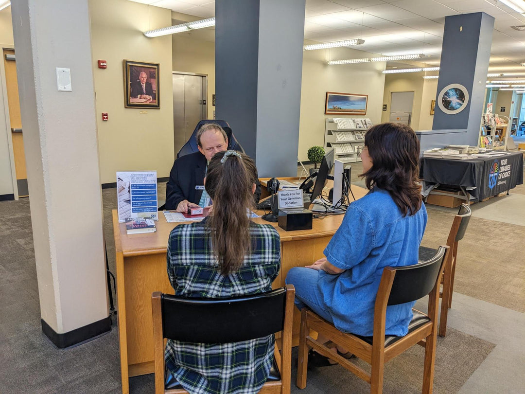 Two people sitting at a wooden desk in front of a notary.