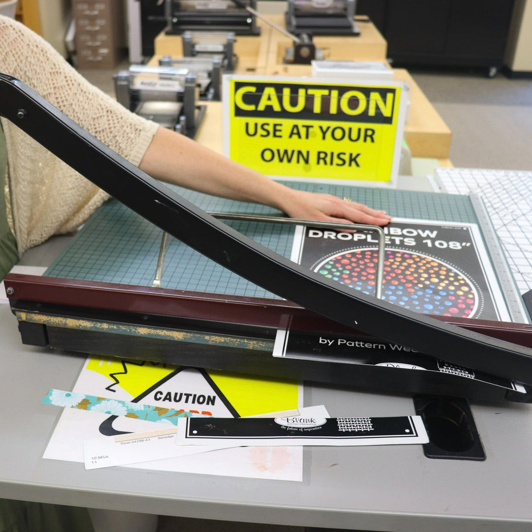 A person using a paper cutter to cut strips of paper.