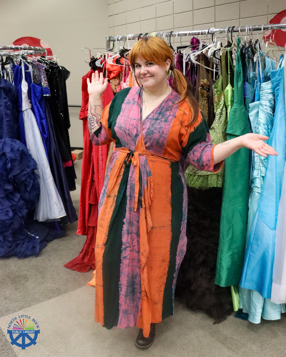Laman teen department manager Jenna stands in front of a rack of colorful formal dresses.