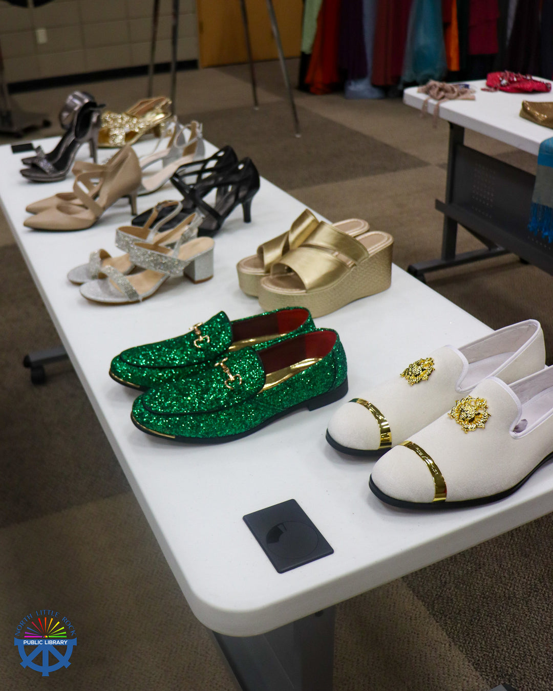 Neutral formal shoes, with one sparkly green pair, on a white banquet table.