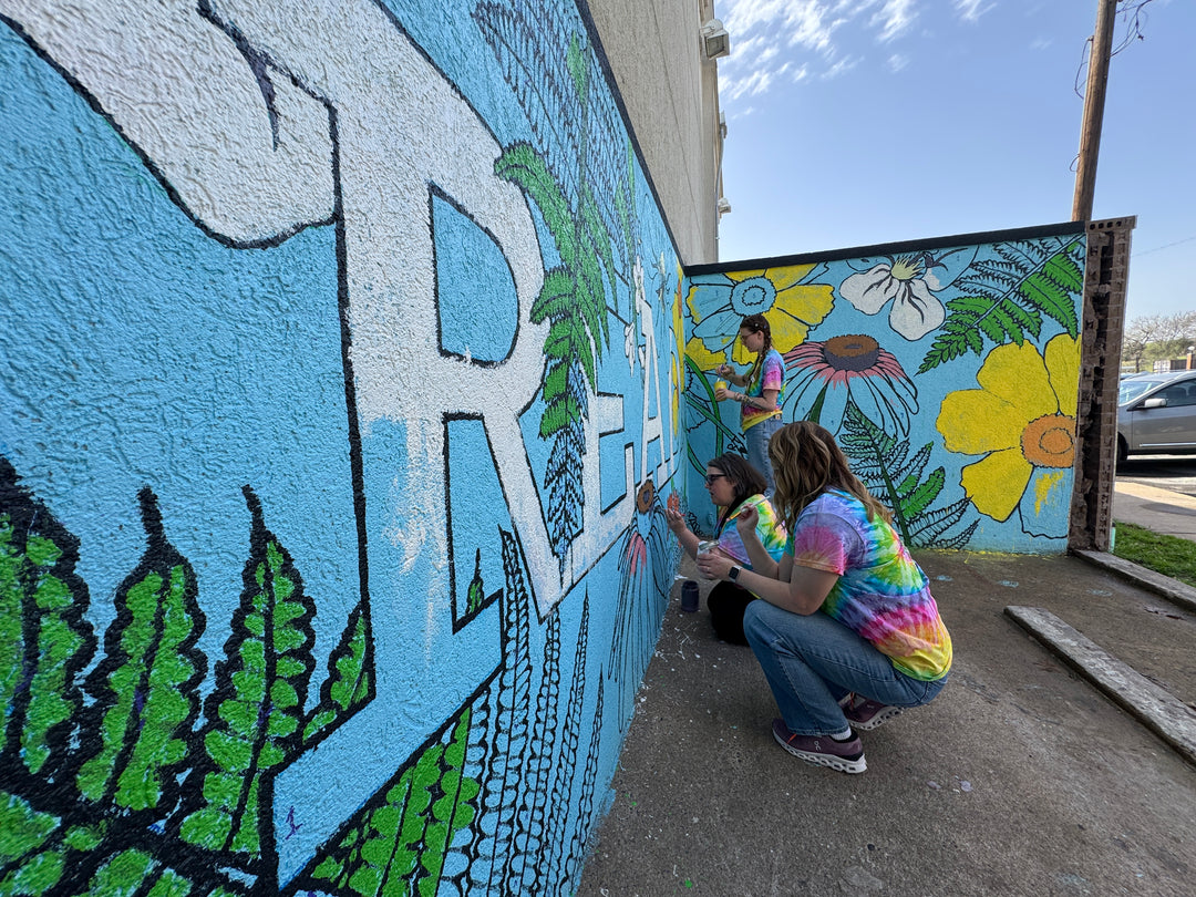 North Little Rock Library creates a colorful READ mural featuring daffodils and coreopsis flowers on a blue background.