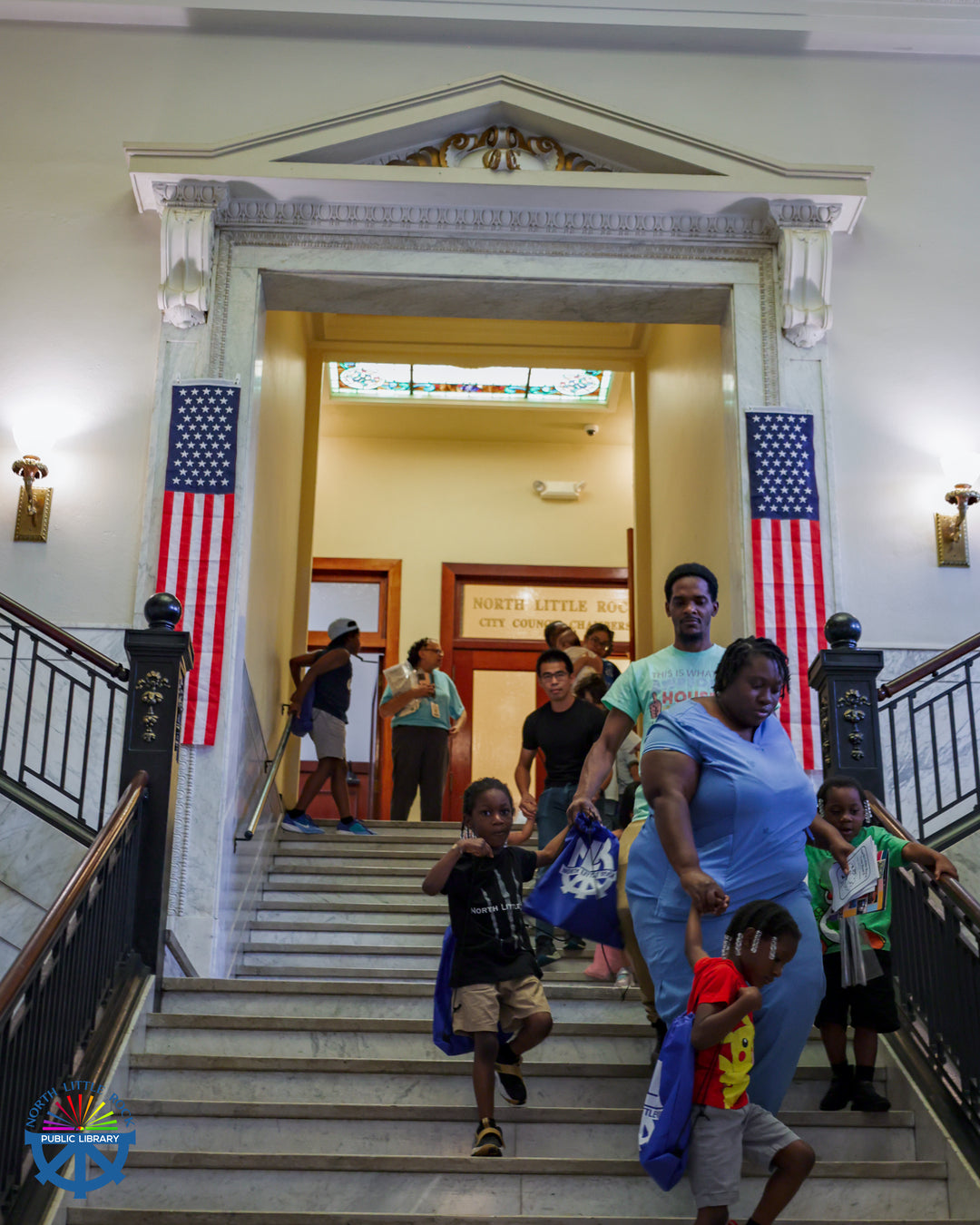 Families walk down a staircase in North Little Rock's City Hall.