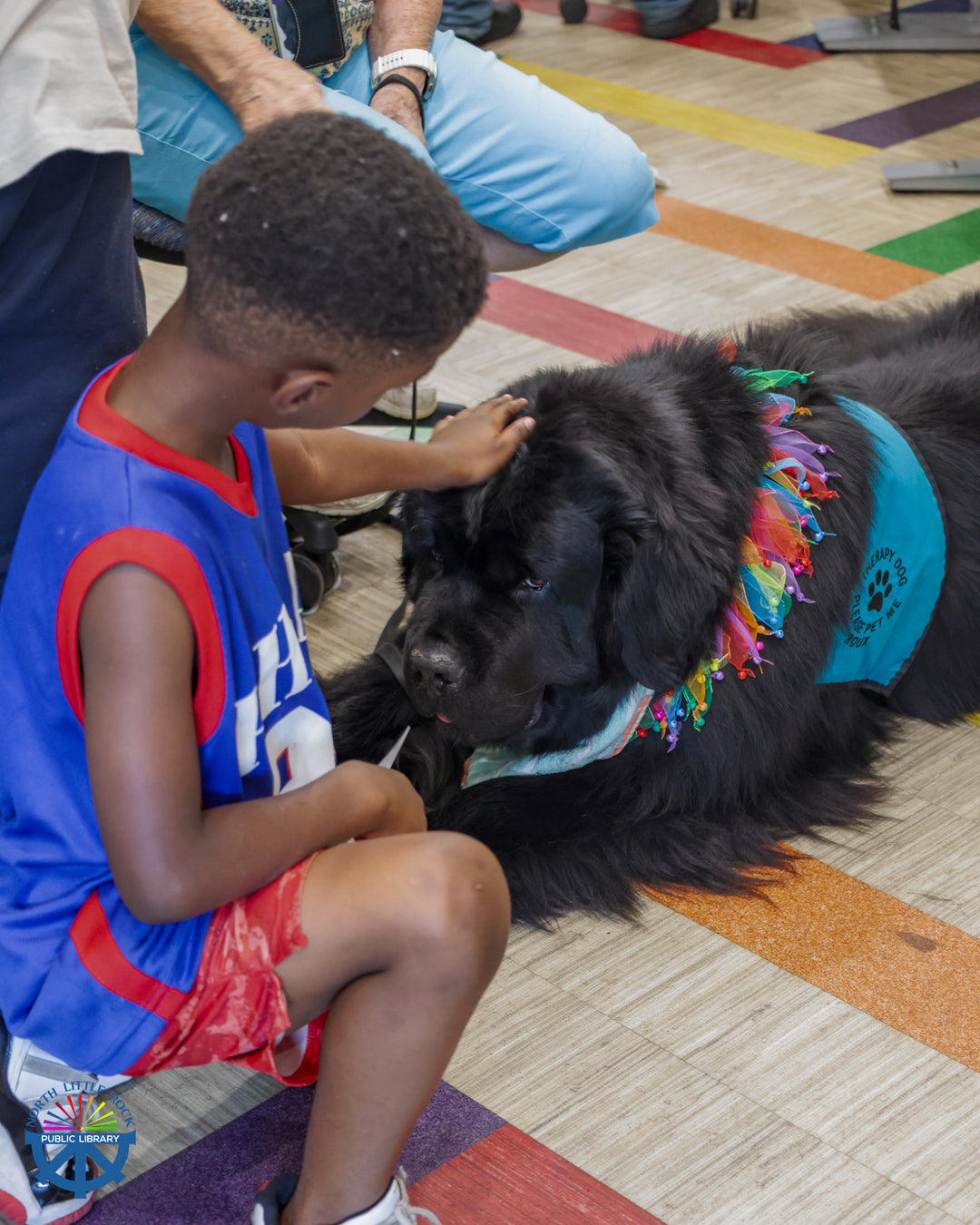 A child pets a large black dog at a Rover stop at the Beacon of Hope Church.