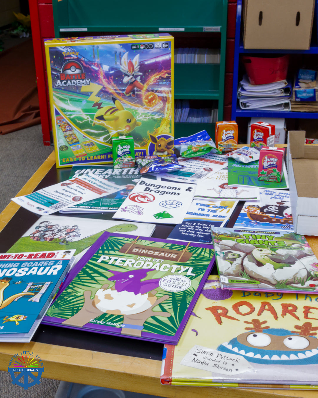 A display a colorful dinosaur-themed books and games on a table.