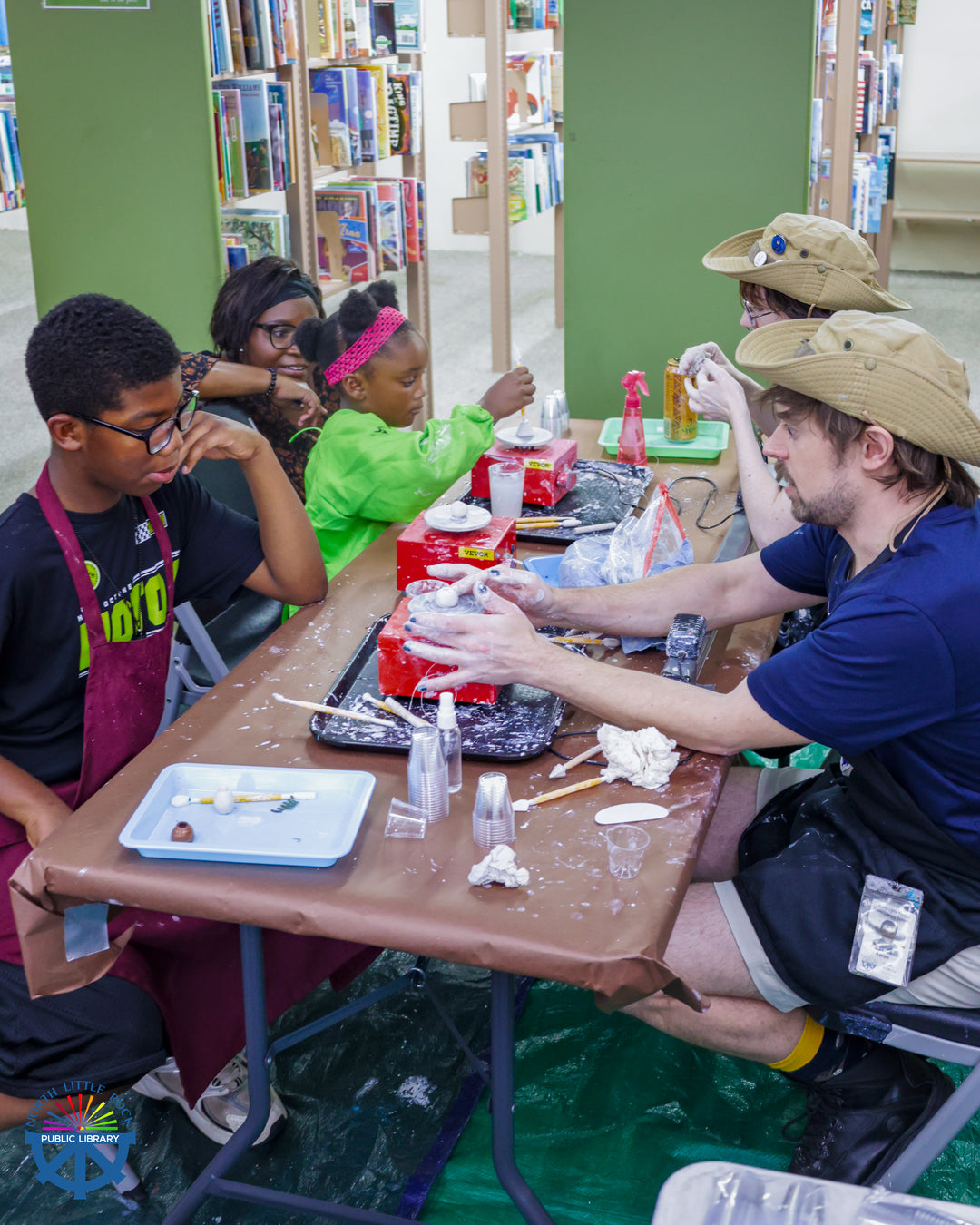 Mobile Makerspace staff members Aaron and Carter show a family how to use miniature pottery wheels.
