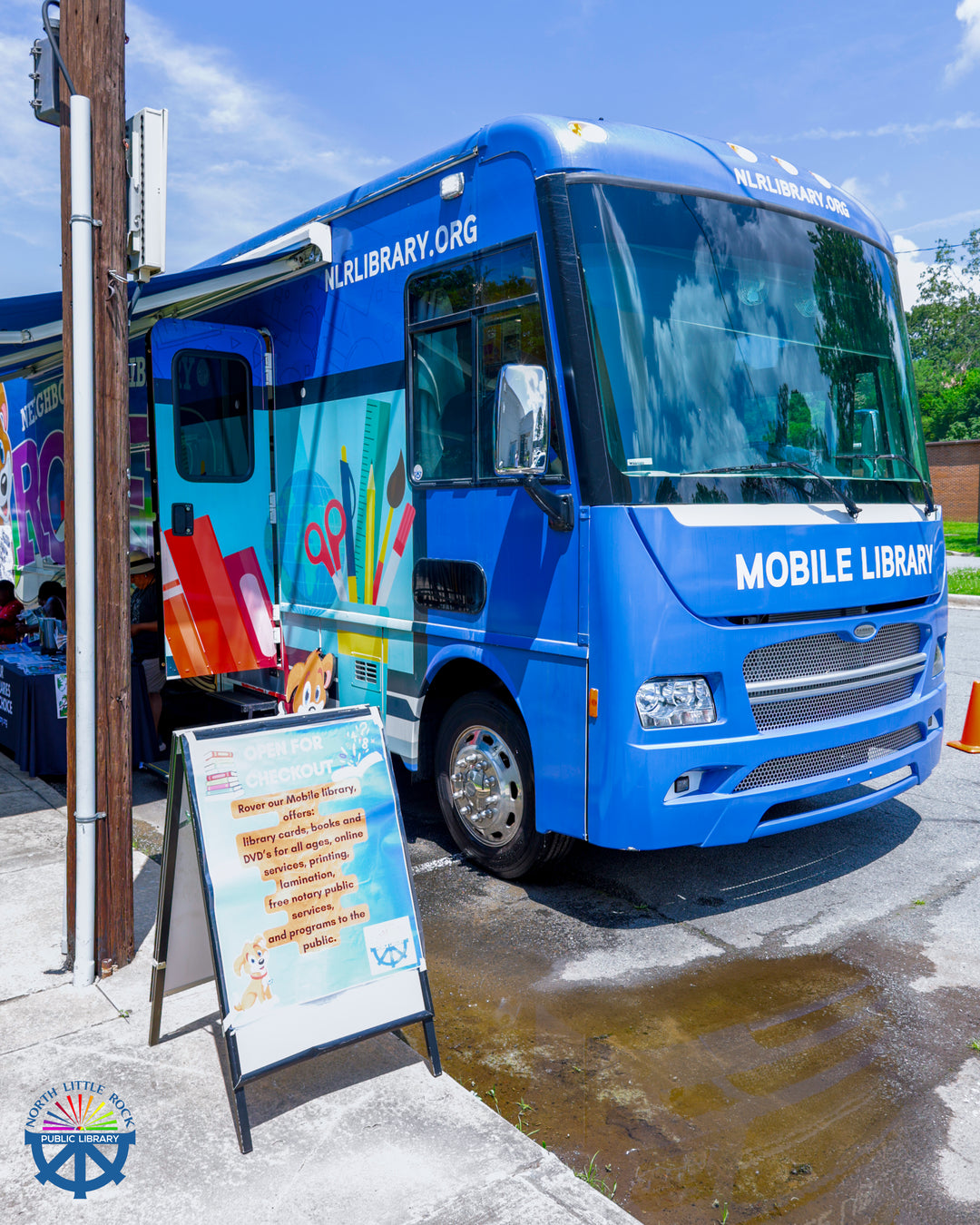 A blue mobile library parked outside the library.