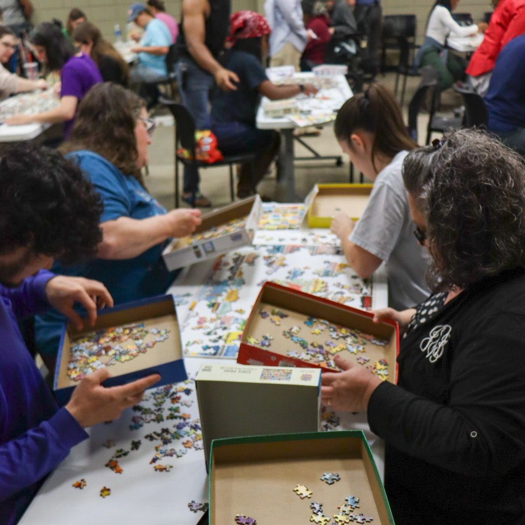 Four people sitting at a table completing a puzzle.