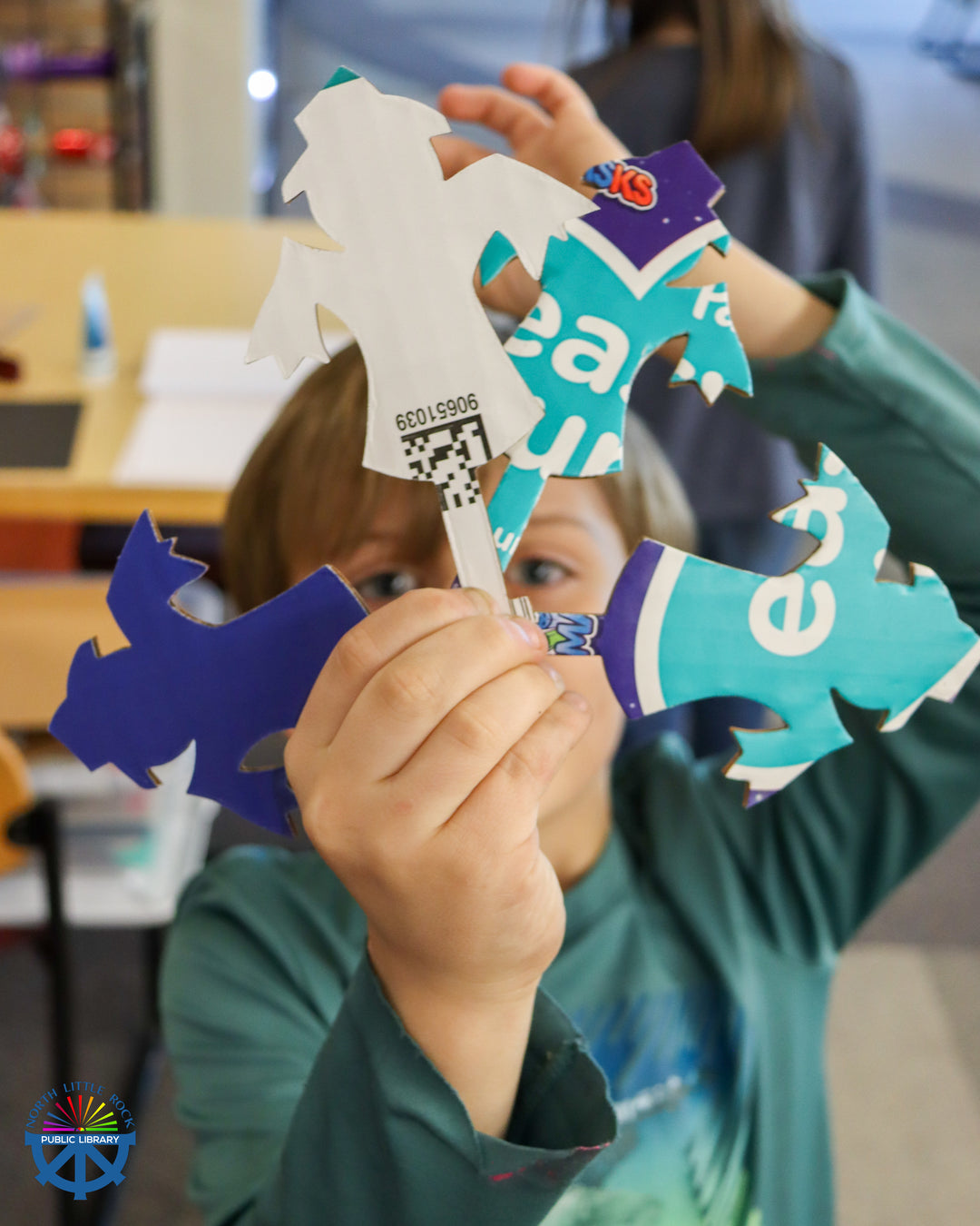 A tween holds up cardboard cutouts of a mysterious figure.