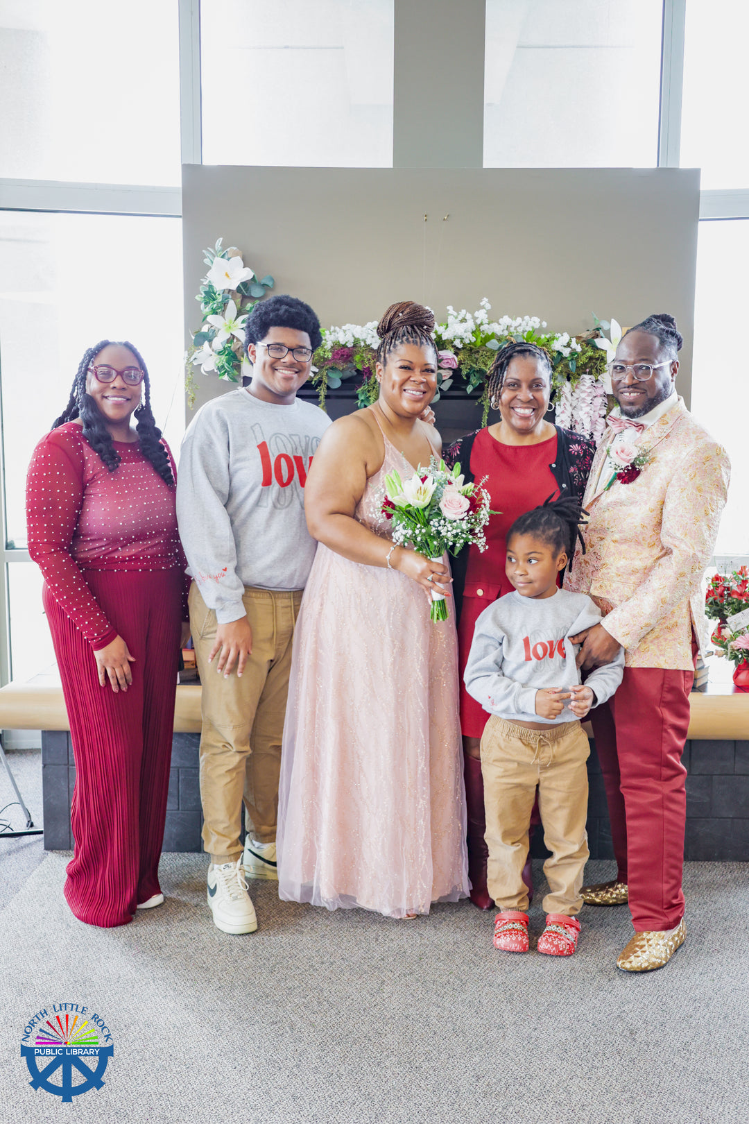 Five adults and one child in coordinating outfits in front of a decorated mantle.
